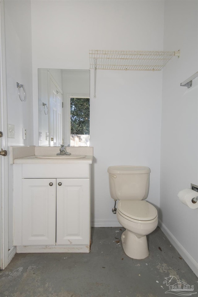 bathroom with vanity, toilet, and concrete floors