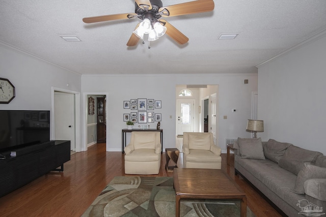 living room featuring ceiling fan, dark hardwood / wood-style flooring, a textured ceiling, and ornamental molding