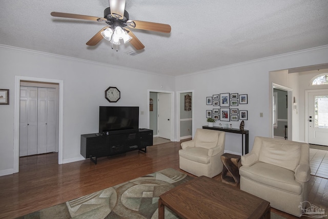 living room featuring ornamental molding, a textured ceiling, ceiling fan, and dark wood-type flooring