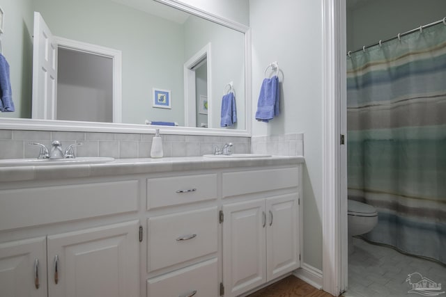 bathroom featuring a shower with shower curtain, backsplash, tile patterned floors, vanity, and toilet