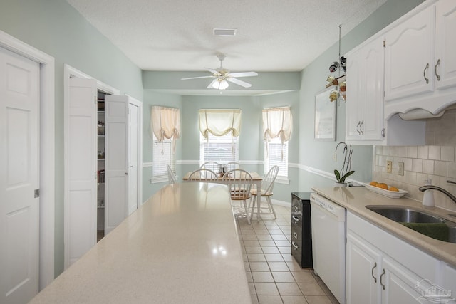 kitchen featuring decorative backsplash, a textured ceiling, white dishwasher, and white cabinetry