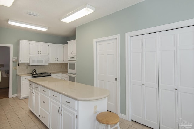 kitchen featuring tasteful backsplash, white cabinetry, light tile patterned floors, and white appliances