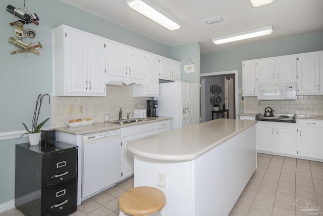 kitchen with sink, a kitchen island, backsplash, white appliances, and white cabinets