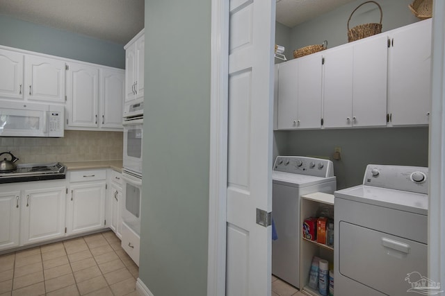 clothes washing area with light tile patterned flooring, cabinets, independent washer and dryer, and a textured ceiling