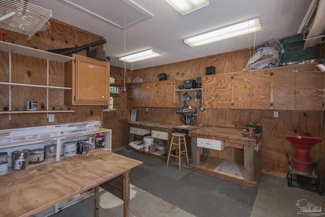 misc room featuring a workshop area, wood walls, and a textured ceiling