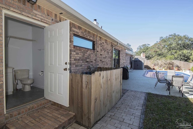 view of patio / terrace with a fenced in pool and a storage shed