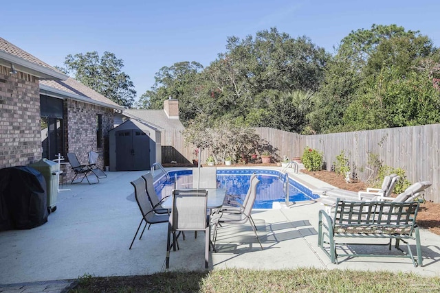 view of swimming pool featuring a grill, a patio, and a shed