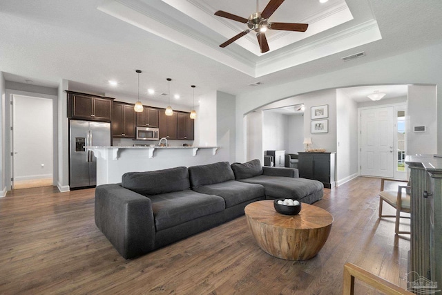 7908 Majestic Cypress Dr, Milton, FL 32583 - living area with visible vents, crown molding, ceiling fan, a tray ceiling, and arched walkways