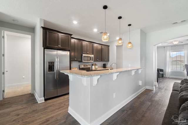 7908 Majestic Cypress Dr, Milton, FL 32583 - kitchen with dark wood-style flooring, visible vents, dark brown cabinets, a breakfast bar, and stainless steel appliances