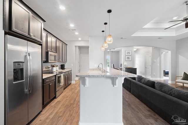 7908 Majestic Cypress Dr, Milton, FL 32583 - kitchen featuring a breakfast bar area, arched walkways, dark brown cabinets, open floor plan, and stainless steel appliances