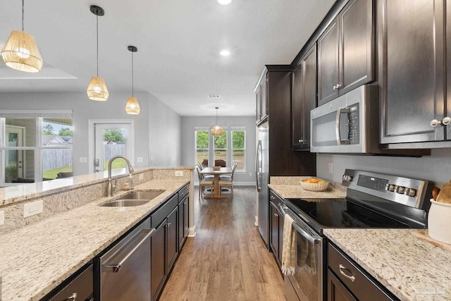 7908 Majestic Cypress Dr, Milton, FL 32583 - kitchen with dark brown cabinets, a sink, light stone counters, stainless steel appliances, and light wood-style flooring