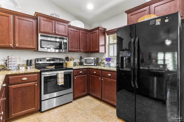kitchen featuring light tile patterned flooring, a toaster, lofted ceiling, appliances with stainless steel finishes, and light stone countertops