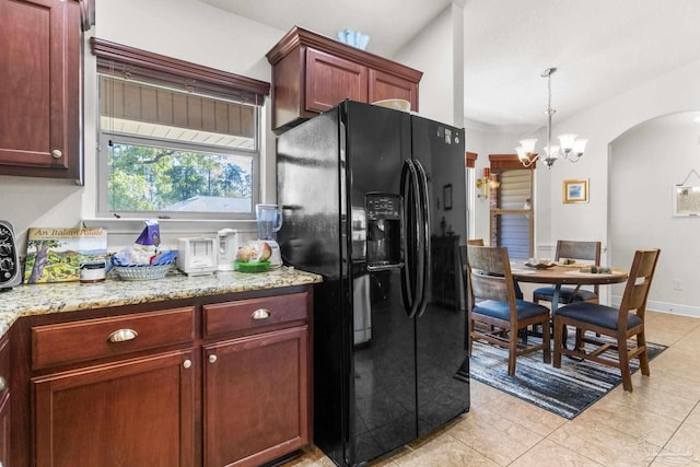 kitchen with light tile patterned floors, arched walkways, pendant lighting, black fridge with ice dispenser, and a chandelier