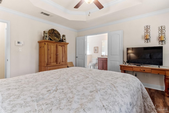 bedroom featuring dark wood-style floors, a raised ceiling, visible vents, connected bathroom, and crown molding