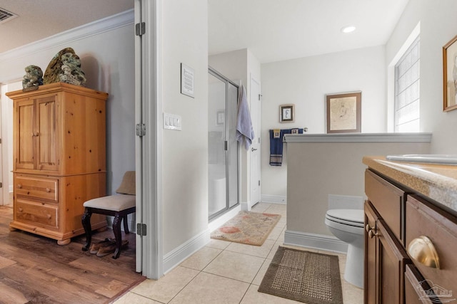 bathroom with a shower stall, toilet, vanity, ornamental molding, and baseboards