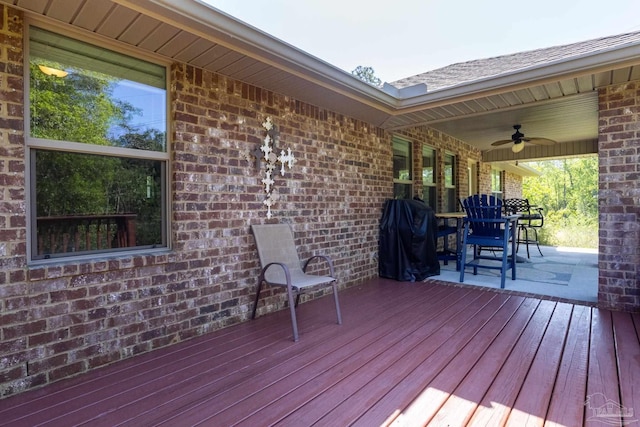 wooden terrace with outdoor dining area, a grill, and a ceiling fan