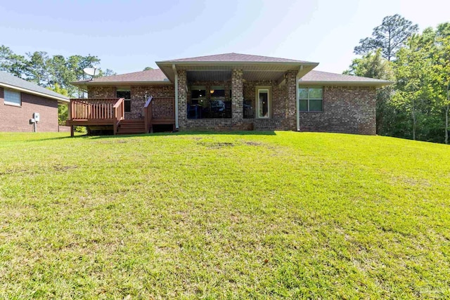 back of property featuring brick siding, a lawn, and a wooden deck