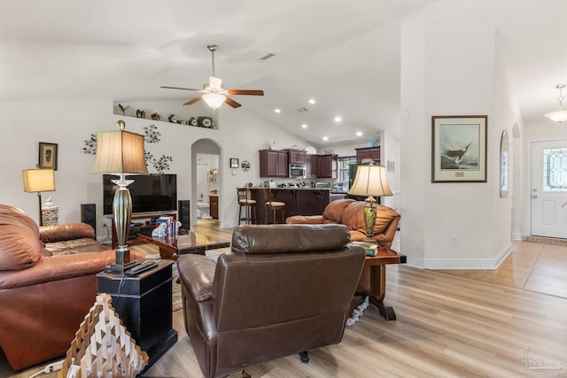 living room with recessed lighting, lofted ceiling, a ceiling fan, arched walkways, and light wood-style flooring
