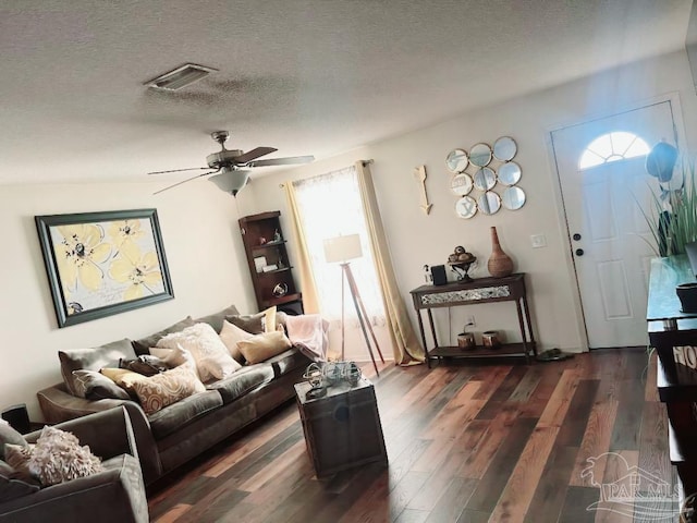 living room featuring ceiling fan, dark hardwood / wood-style floors, and a textured ceiling