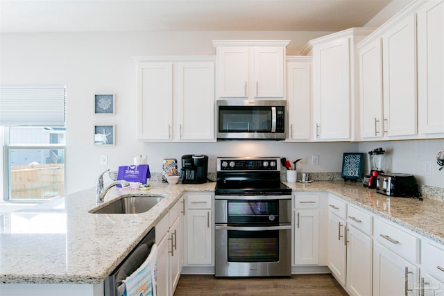 kitchen featuring white cabinets, stainless steel appliances, sink, and light stone countertops