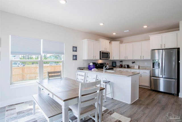 kitchen with light stone counters, sink, white cabinets, stainless steel appliances, and dark hardwood / wood-style flooring