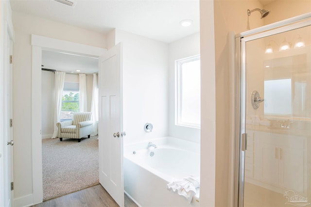 bathroom with wood-type flooring, shower with separate bathtub, and sink