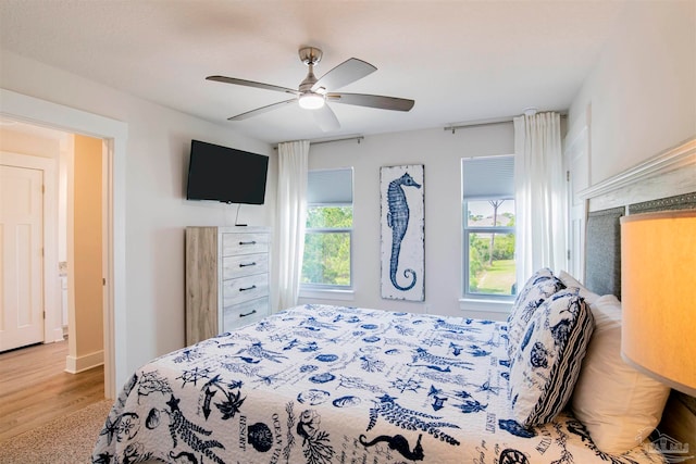 bedroom featuring multiple windows, hardwood / wood-style floors, and ceiling fan