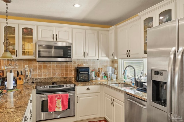 kitchen featuring white cabinetry, hanging light fixtures, sink, appliances with stainless steel finishes, and backsplash