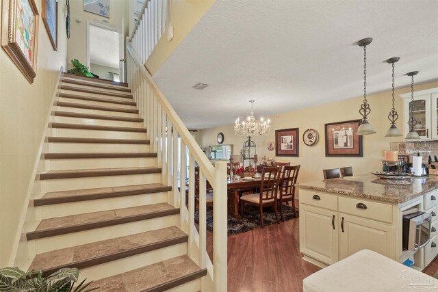 stairway with dark hardwood / wood-style floors and a chandelier