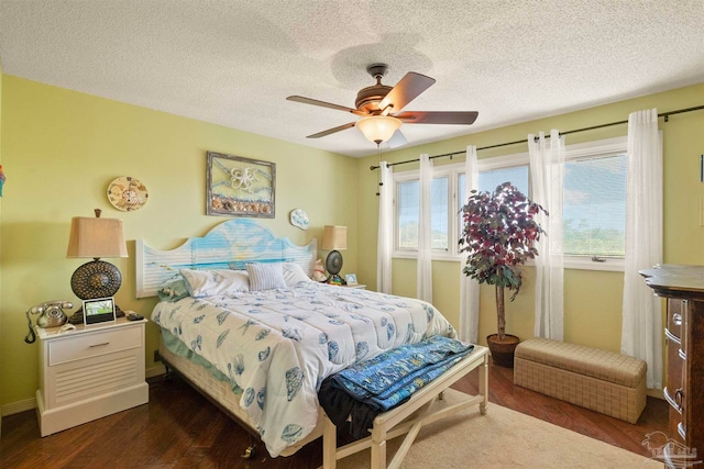 bedroom featuring dark wood-type flooring, a textured ceiling, and ceiling fan