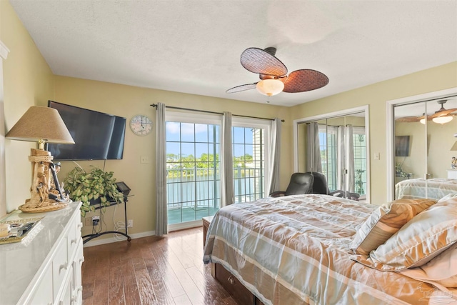 bedroom with dark hardwood / wood-style flooring, multiple closets, ceiling fan, and access to exterior