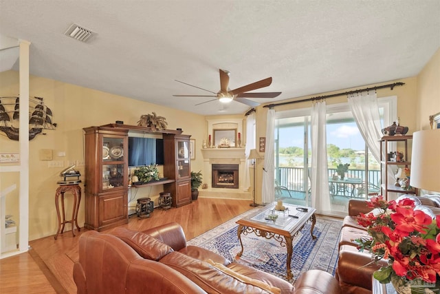 living room featuring light hardwood / wood-style floors, a textured ceiling, and ceiling fan