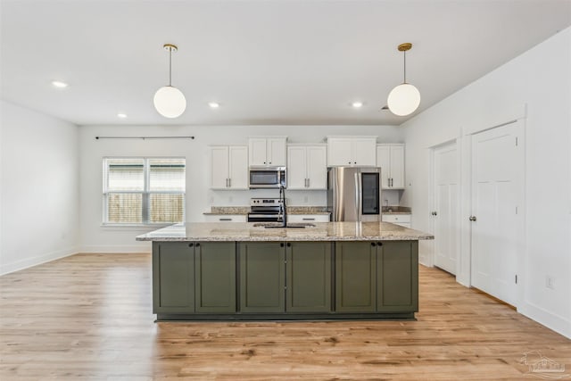 kitchen featuring decorative light fixtures, light stone countertops, white cabinets, and appliances with stainless steel finishes