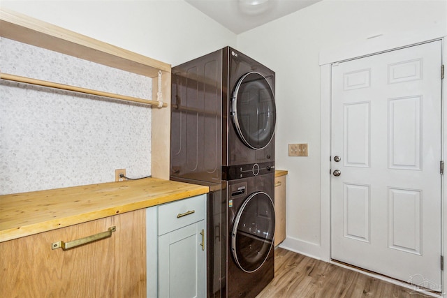 laundry room featuring light hardwood / wood-style flooring, cabinets, and stacked washer / dryer