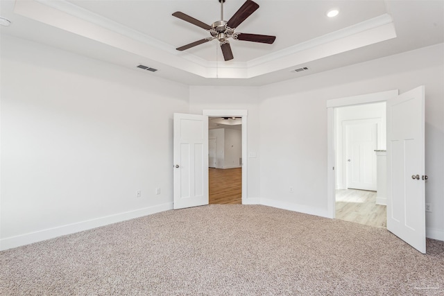 spare room featuring ceiling fan, light colored carpet, ornamental molding, and a tray ceiling