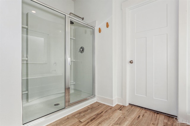 bathroom with an enclosed shower and hardwood / wood-style floors