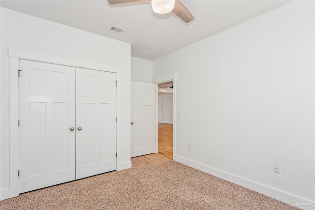 unfurnished bedroom with light carpet, ceiling fan, and a closet