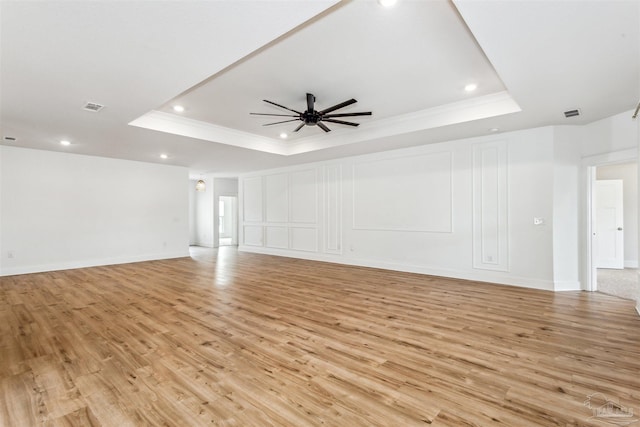 unfurnished living room featuring a raised ceiling, ceiling fan, and light hardwood / wood-style floors