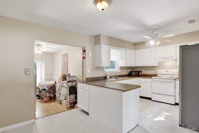kitchen featuring a peninsula, white range with electric cooktop, freestanding refrigerator, and ceiling fan
