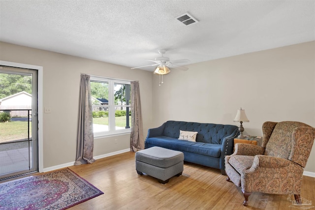 living area featuring baseboards, light wood-style flooring, visible vents, and a wealth of natural light