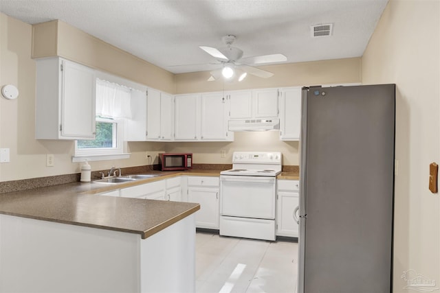kitchen with white range with electric stovetop, a sink, a peninsula, under cabinet range hood, and freestanding refrigerator