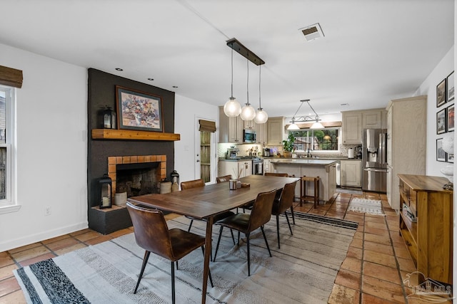 dining area with a fireplace, sink, and light tile patterned floors