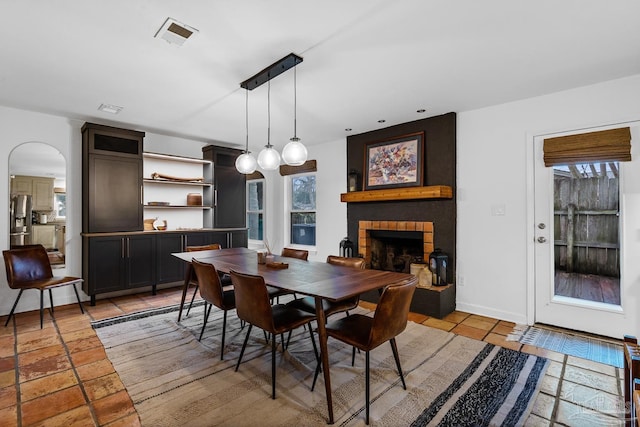 dining room with a fireplace, light tile patterned floors, and a wealth of natural light