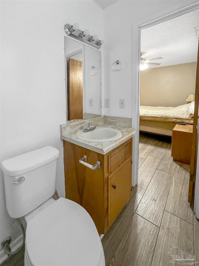 bathroom featuring toilet, ceiling fan, a textured ceiling, and vanity