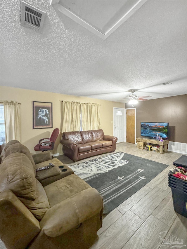 living room featuring ceiling fan, a textured ceiling, and hardwood / wood-style flooring