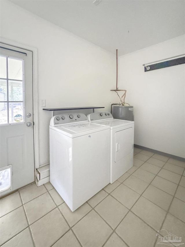 clothes washing area with washer and clothes dryer, water heater, and light tile patterned floors