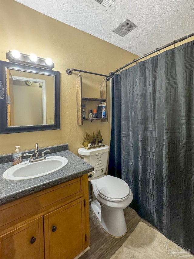 bathroom with toilet, vanity, hardwood / wood-style flooring, a textured ceiling, and curtained shower