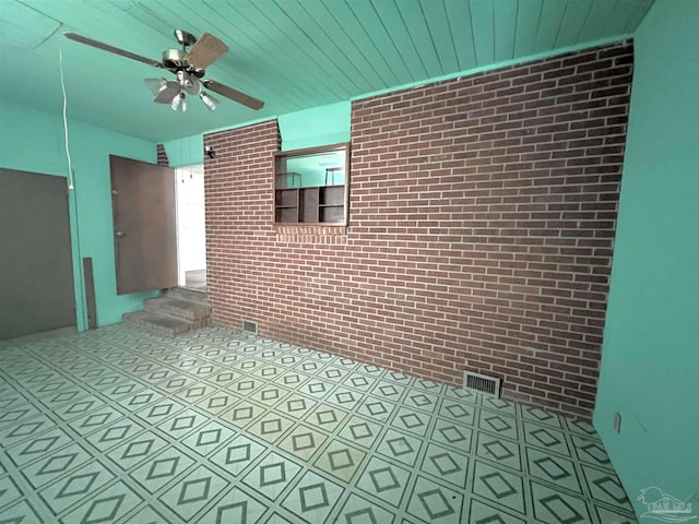 tiled spare room with brick wall and ceiling fan