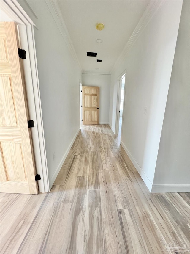 hallway with light wood-type flooring, baseboards, and ornamental molding