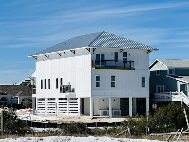 back of property with metal roof, a balcony, and board and batten siding